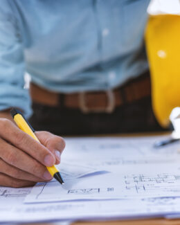 Close up of concentrated male engineer drawing hands working on architectural project at construction site.